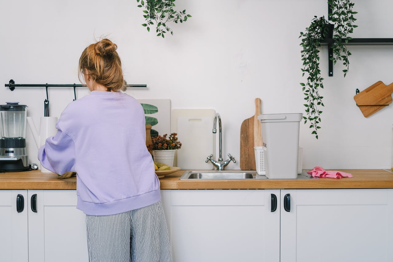 about-01 Back view of unrecognizable young female in casual clothes standing at wooden counter in light kitchen in daytime